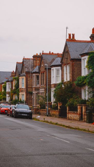 The image depicts a row of traditional brick terraced houses along a residential street, with the lower portions of the buildings visible up to the first or second floor. Each house features character